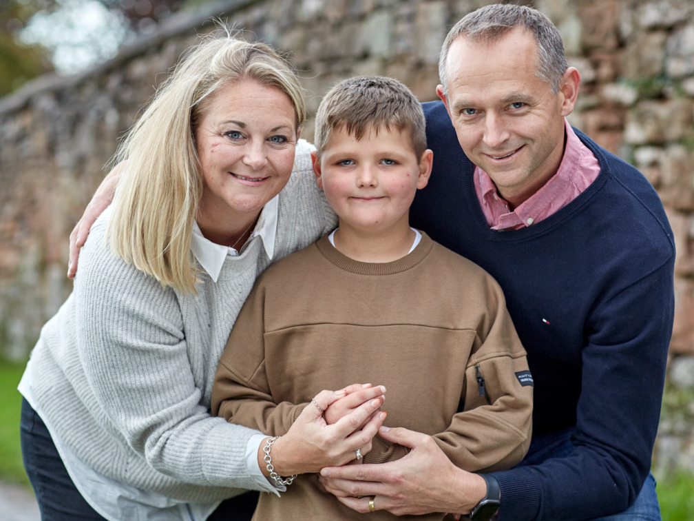 Tommy, aged seven, hugging his two parents